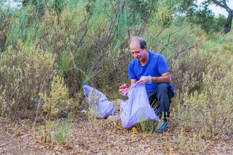 Environmentalist man with garbage bags picking up garbage from the field and taking care of the environment