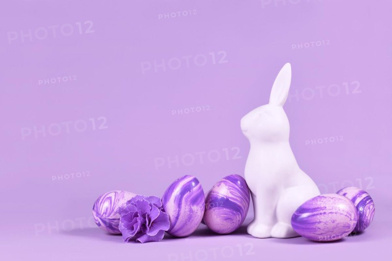 Easter eggs next to bunny figure on violet background