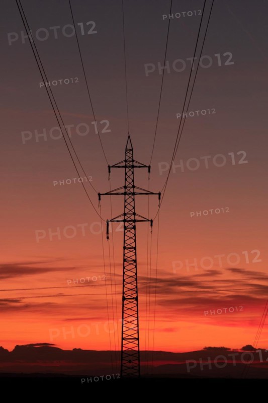 Silhouette of high voltage lines and transmission towers thru the Moravian field at sunrise