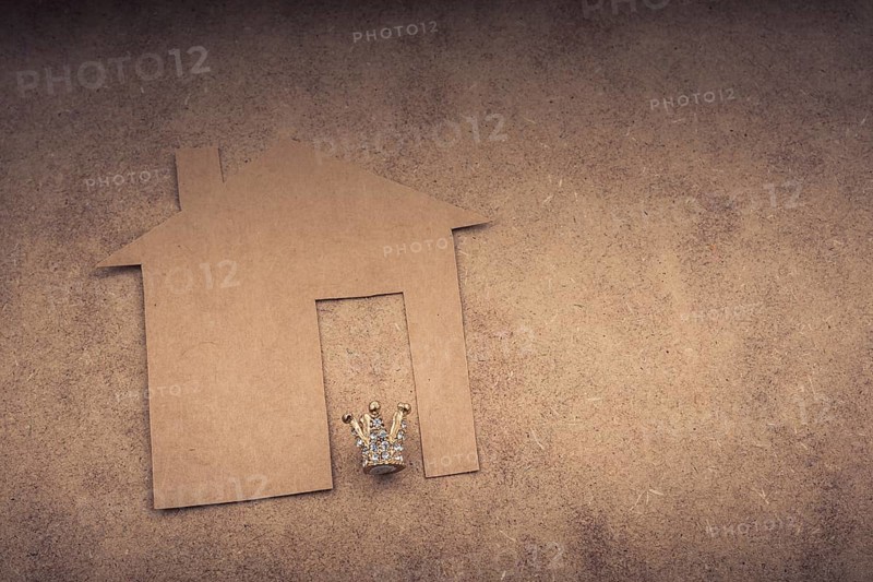 Litle model crown and paper house on a brown background