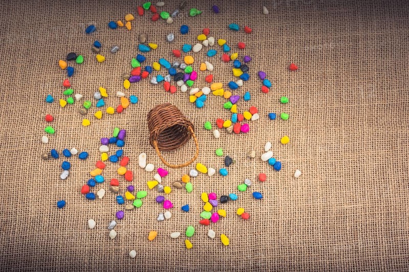Basket and spilled pebbles on canvas background