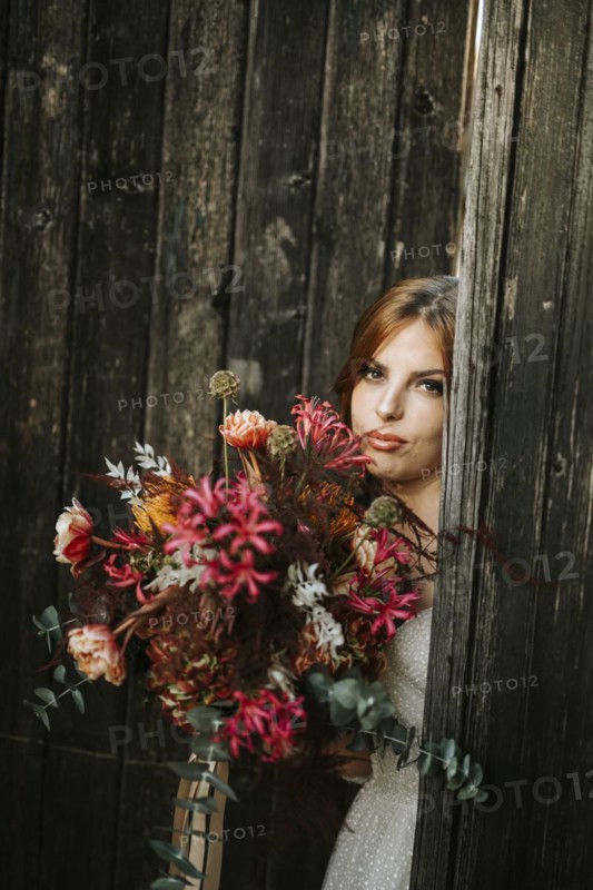 Beautiful bride with a bouquet with wooden door background as a background