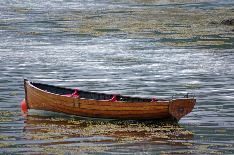 Small wooden rowing boat lying in the shallow waters of Plockton Harbour