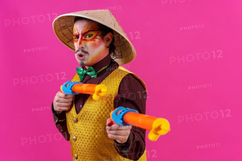 Clown with white facial makeup on a pink background