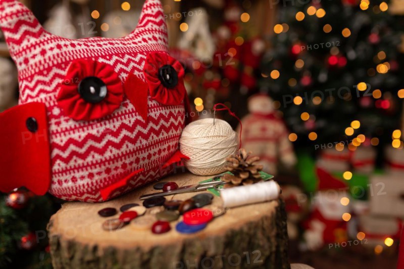 Grandmother sews a plush owl in Christmas arrangement. In studio