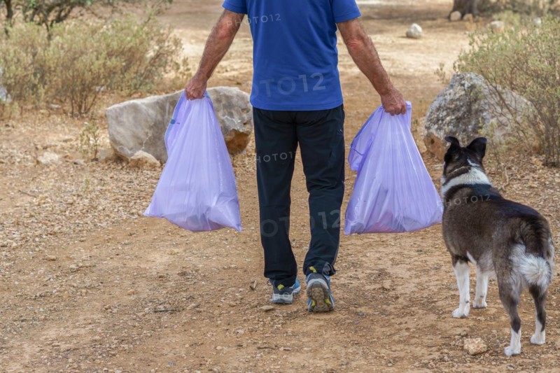 Environmentalist man with garbage bags picking up garbage from the field and taking care of the environment