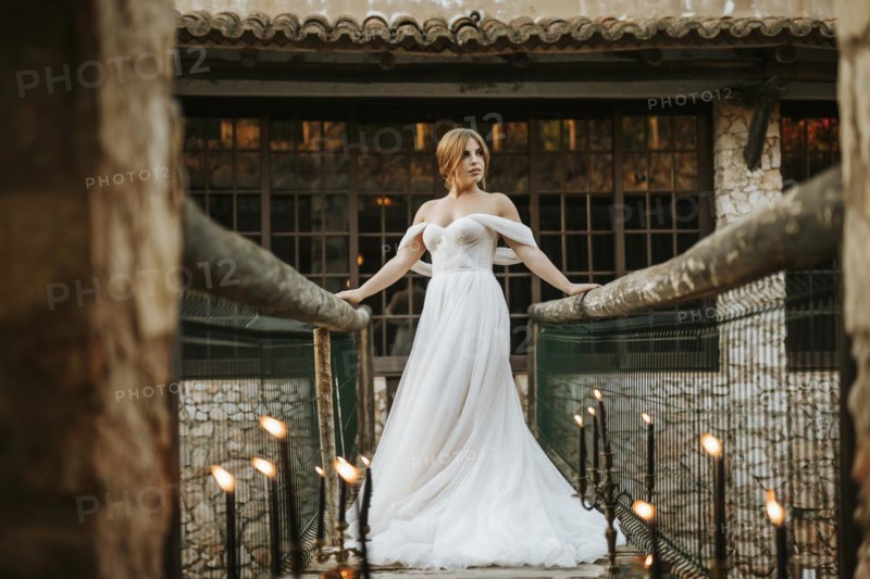 Beautiful rustic bride posing on wooden bridge full of candles