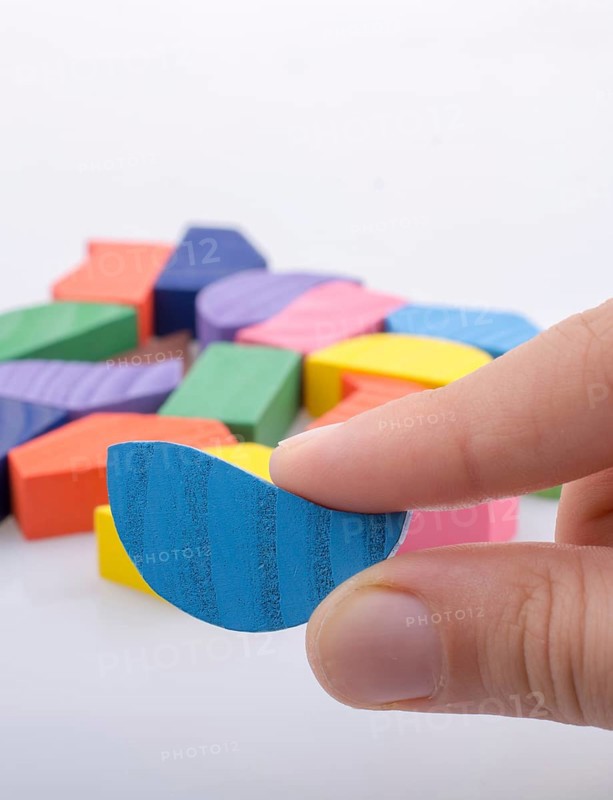 Colorful wooden pieces of a logic puzzle in hand