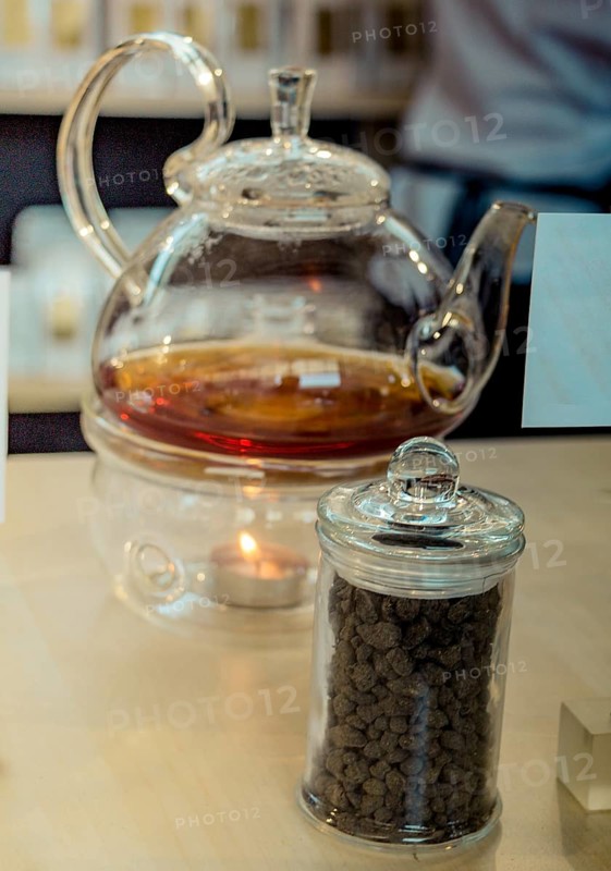 Herbal tea brewed in glass teapot and tea plant in a bottle
