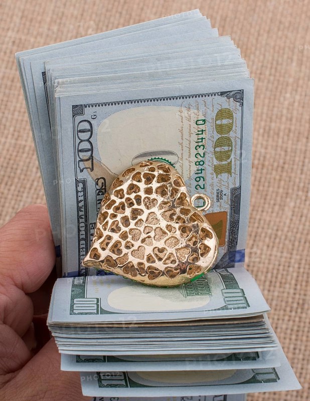 American 100 dollar banknotes with a heart clip in hand