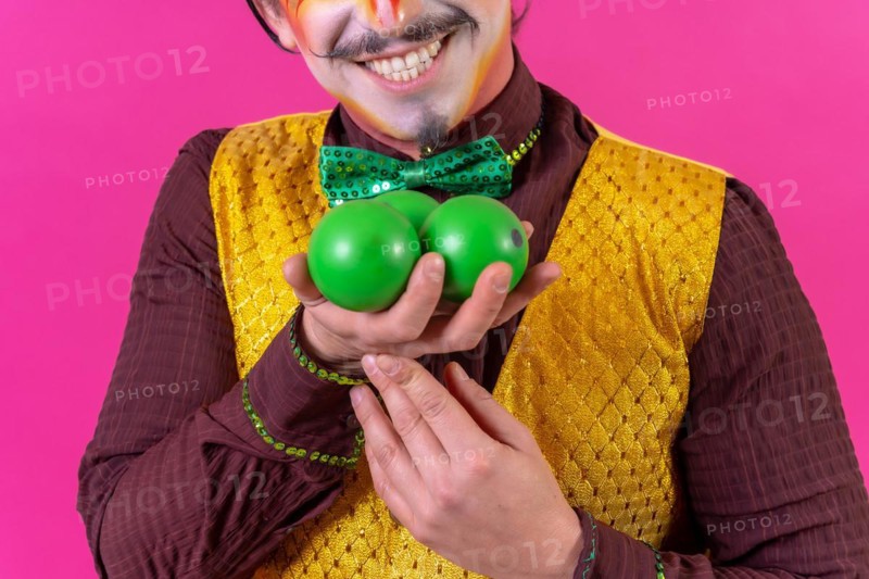 Portrait of clown with white facial makeup on a pink background