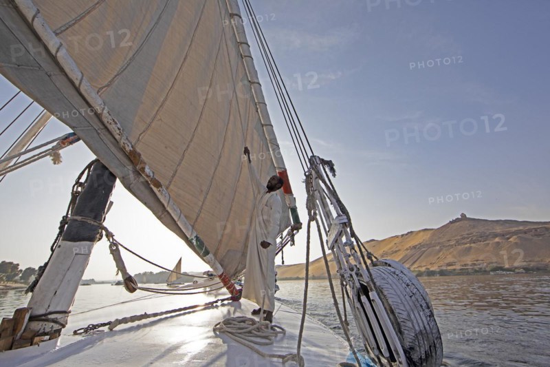 Egyptian man adjusts the sail of a felucca on the Nile