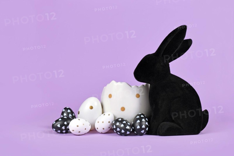 Black and white easter eggs with dots next to bunny figure on violet background