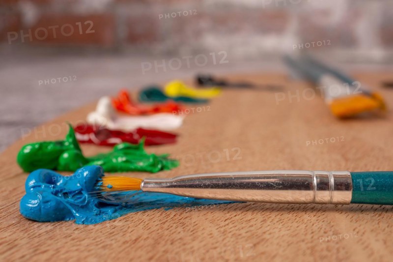 Close-up brush with out-of-focus oil paint colors on a wooden palette