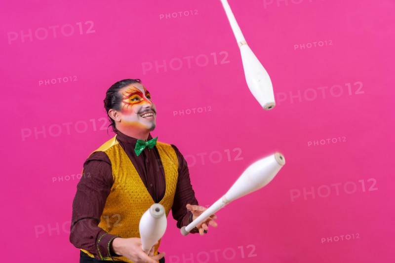Clown with white facial makeup on a pink background