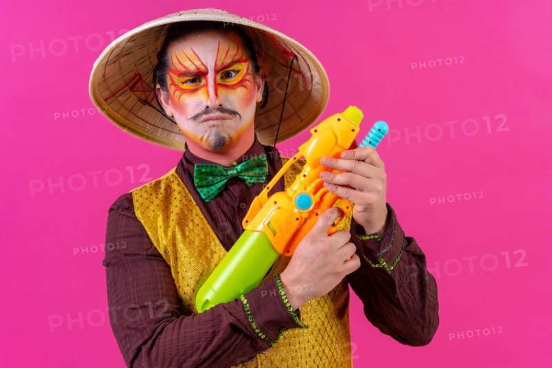 Clown with white facial makeup on a pink background