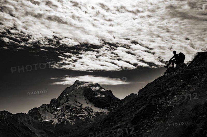 Mountaineer in backlight with cloudy sky in front of Ortler summit massif