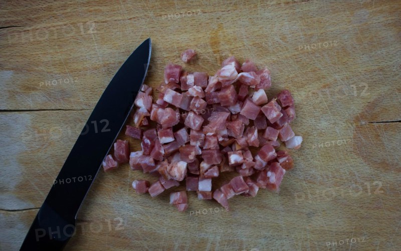 Diced ham and a knife on a wooden board