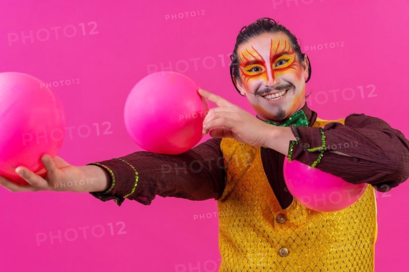 Clown with white facial makeup on a pink background