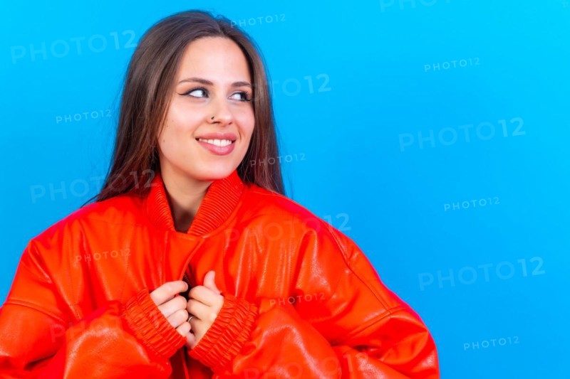 Close up portrait of young caucasian woman in red windbreaker isolated on blue background