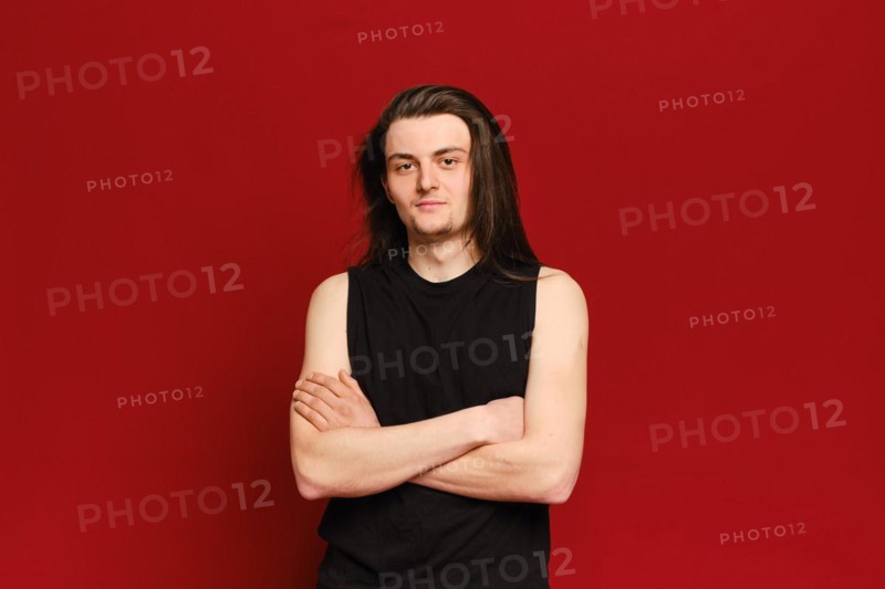Studio portrait of young handsome man with long black hair over red background