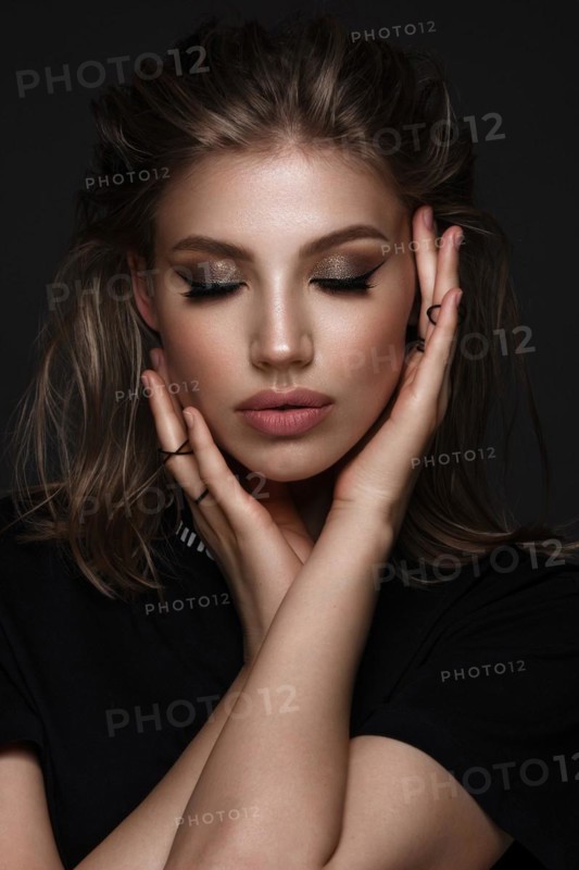 Portrait of a beautiful woman in a black dress with creative makeup in a fashion style. Beauty face. The photo was taken in a studio on a black background