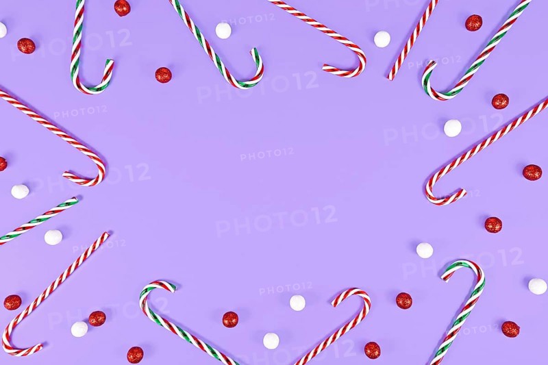 Christmas Candy canes forming frame around purple background with copy space
