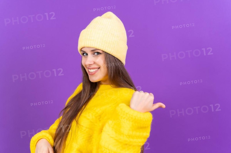 Attractive woman smiling pointing fingers at copy space on purple background
