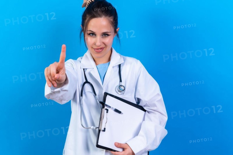 Portrait of smiling female doctor in medical gown standing isolated on blue