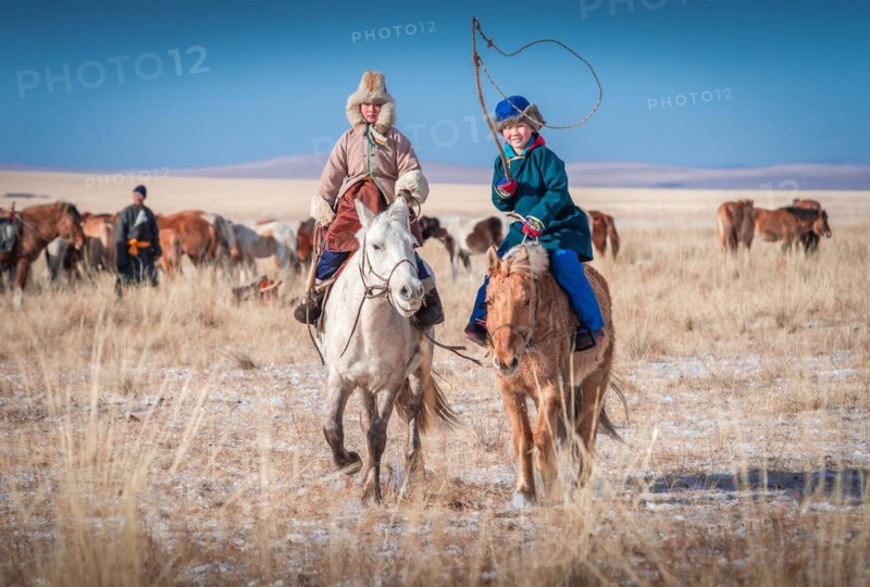 Happy children riding horses in winter. Dornod Province. Mongolia