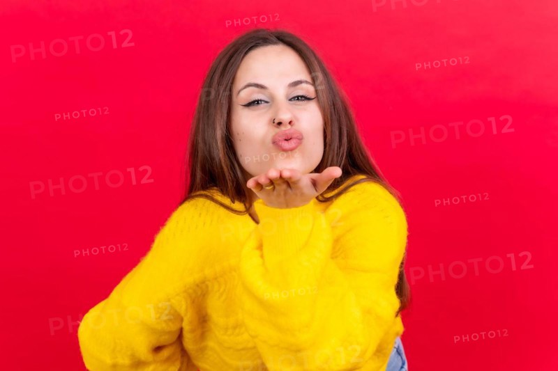 Photo portrait of a young woman blowing a kiss isolated on a red background