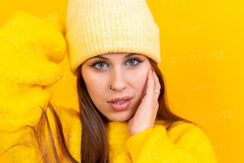 Close up portrait of young caucasian woman in woolen sweater isolated on yellow background
