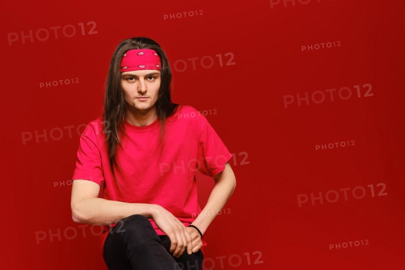 Studio portrait of confident young man with red head band and shirt