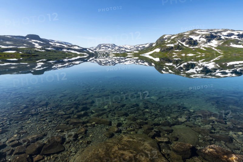 Reflection of partly snow-covered mountains in Lake Stavatn in Haukelifjell