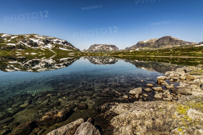 Reflection of partly snow-covered mountains in Lake Stavatn in Haukelifjell