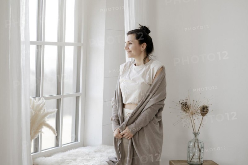 Dark-haired woman stands relaxed at the window