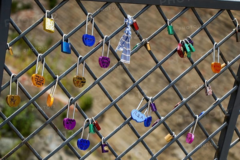 Many colorful metal love padlocks on fence
