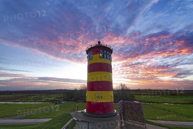 Pilsum lighthouse at sunset on the dyke near Greetsiel in the Krummhoern region on the East Frisian North Sea coast