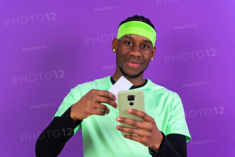 Black ethnic man with a phone in green clothes on a pink background
