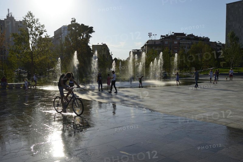 Fountain and cyclists in the backlight