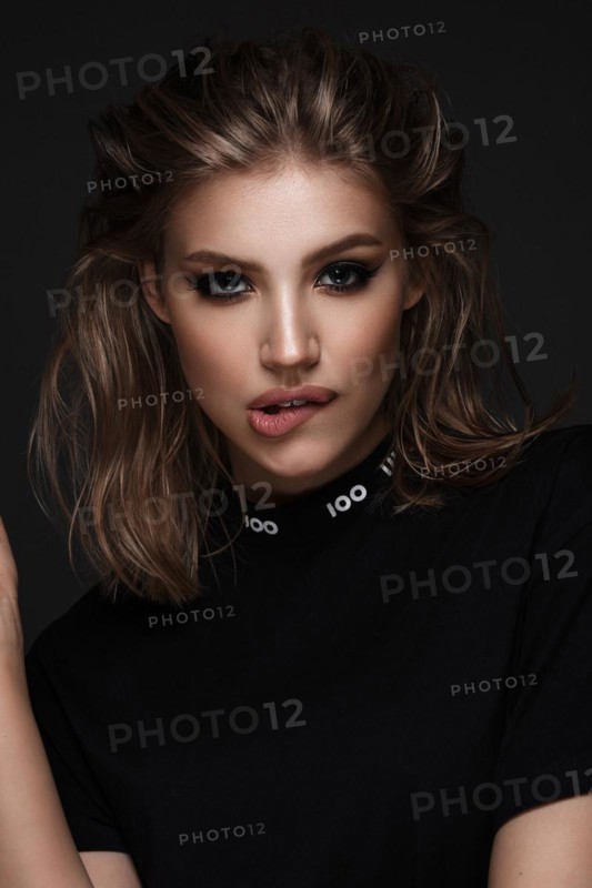 Portrait of a beautiful woman in a black dress with creative makeup in a fashion style. Beauty face. The photo was taken in a studio on a black background
