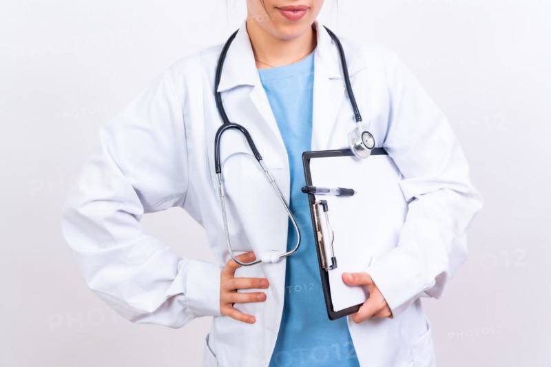 Happy beautiful female doctor in medical coat standing isolated on white