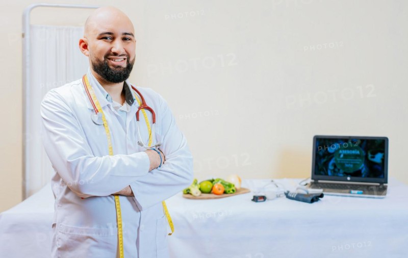 Portrait of smiling male nutritionist at his workplace. Smiling nutritionist doctor with crossed arms in her office. Portrait of smiling professional nutritionist