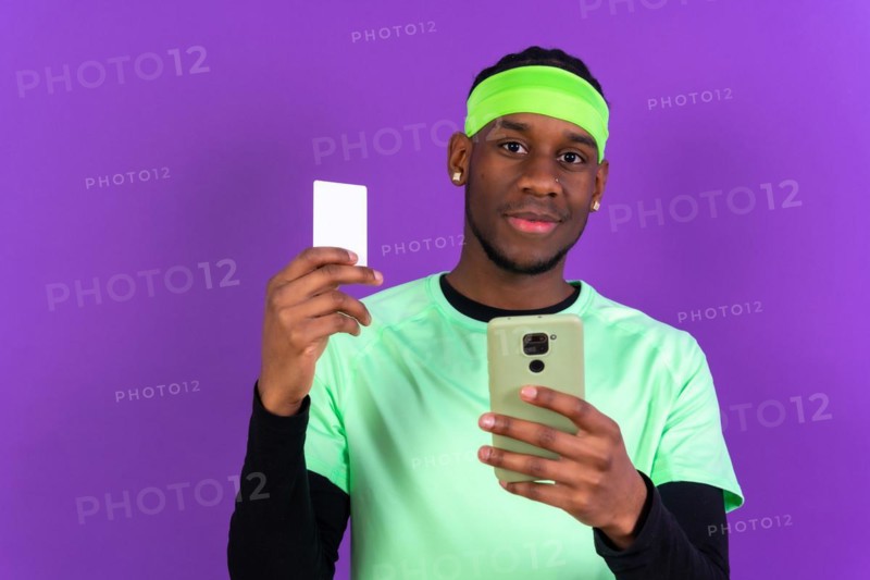 Black ethnic man with a phone in green clothes on a pink background