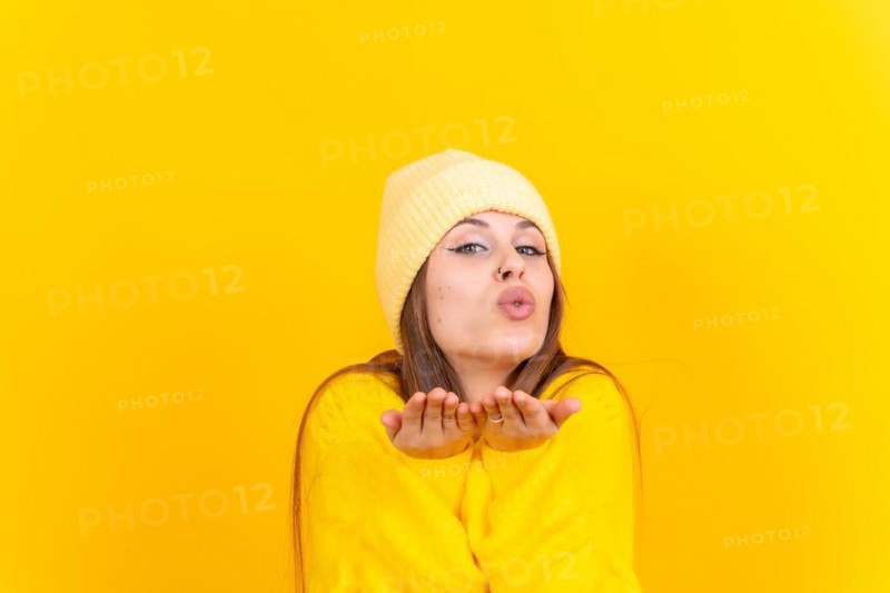 Photo portrait of a young woman blowing a kiss isolated on a yellow background