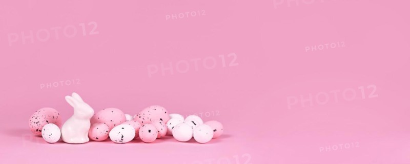Banner with white and pink Easter eggs with small bunny sculpture on pink background with copy space
