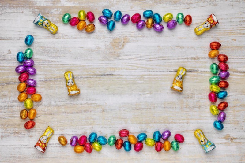 Frame of colourful Easter sweets on wood