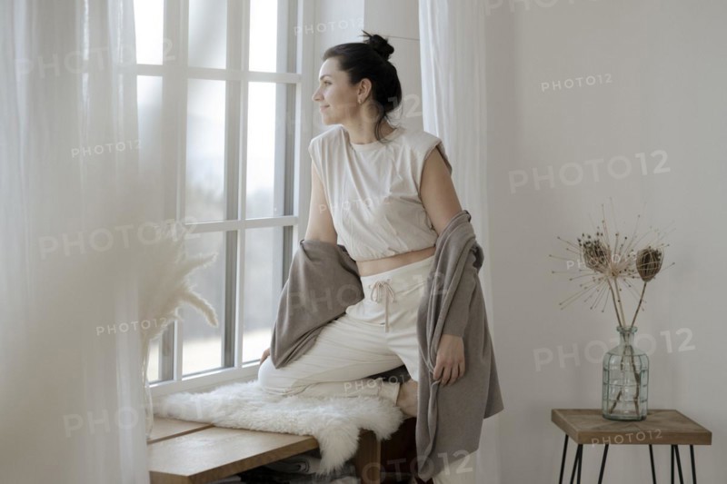 Dark-haired woman sits relaxed at the window