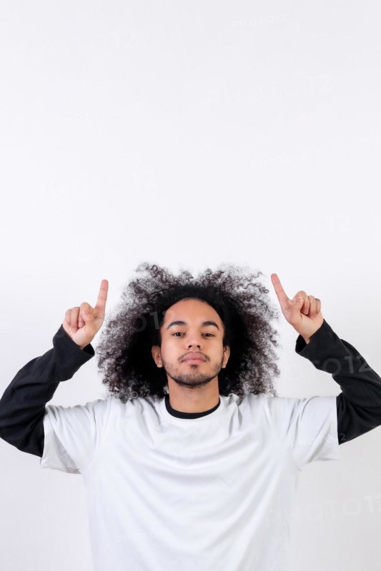 Pointing above a copy paste space. Young man with afro hair on white background