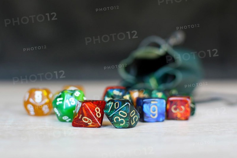 Different colorful role playing dice on table with blurry storage leather bag in background